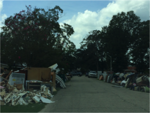 People's ruined possessions line the street in a flooded area.