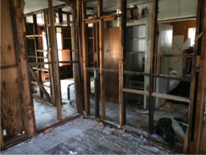 The inside of a flooded home. Ruined sheetrock has been removed leaving only studs.